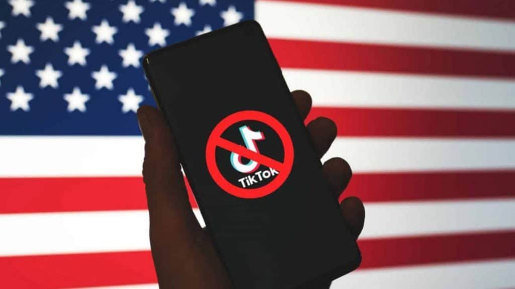 Bandeira dos EUA, com o logo do TikTok à frente e um ícone de bloqueio à sua frente