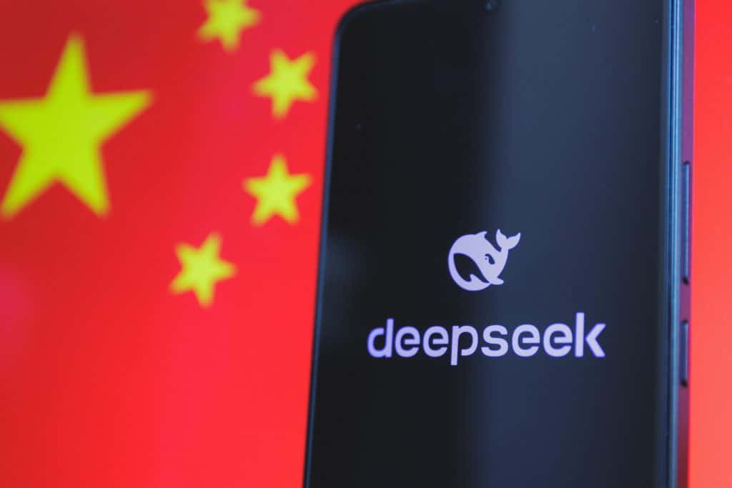 Logo do DeepSeek em um smartphone; ao fundo, parte da bandeira da China desfocada