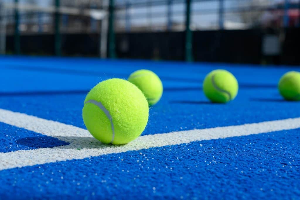 Bolas de tênis dispostas em uma quadra azul