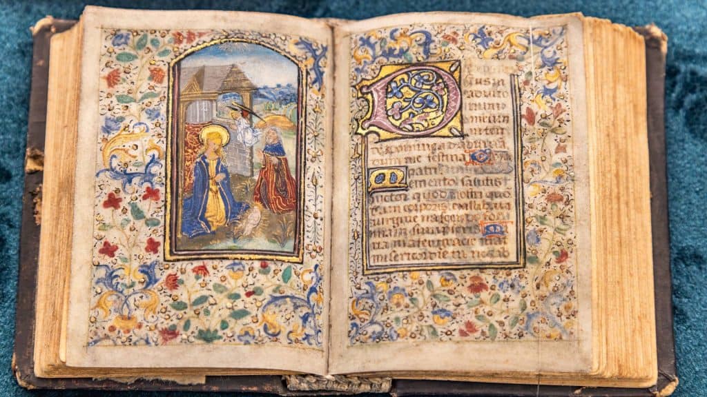 Detalhe de uma bíblia manuscrita com escrita latina e floreios de ouro - Mulheres escribas