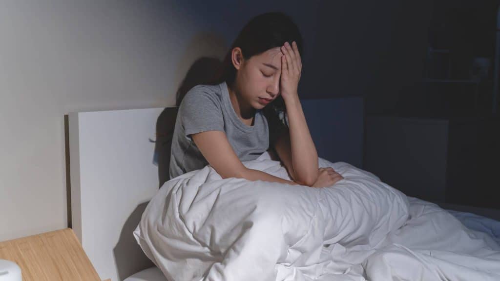 Mulher na cama tentando dormir