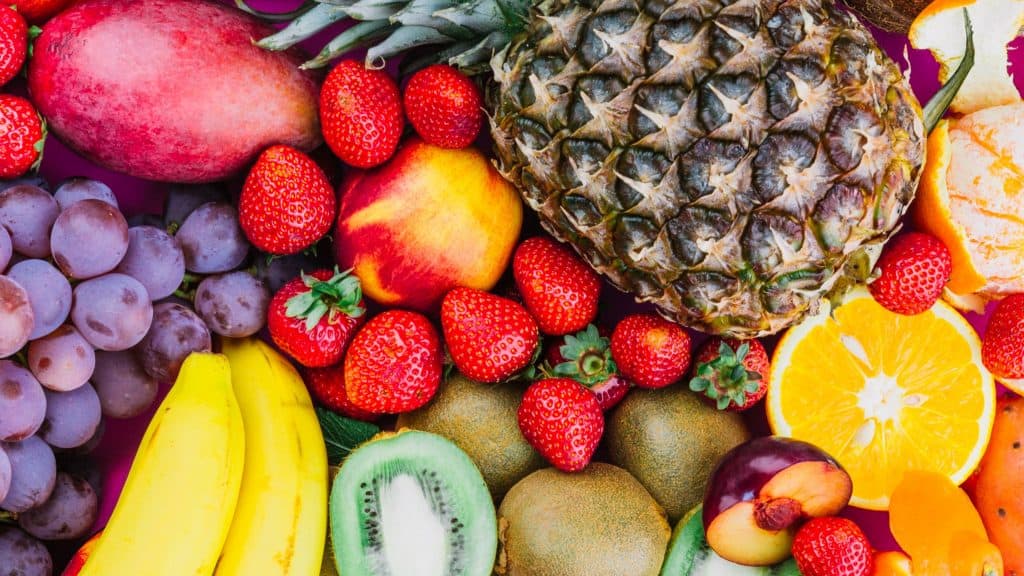 imagem com diversas frutas como abacaxi, morango, kiwi, banana, uva, pessego e manga