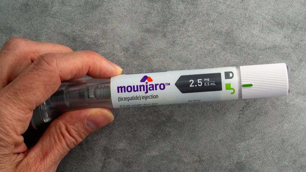 Mão segurando uma caneta injetável Mounjaro