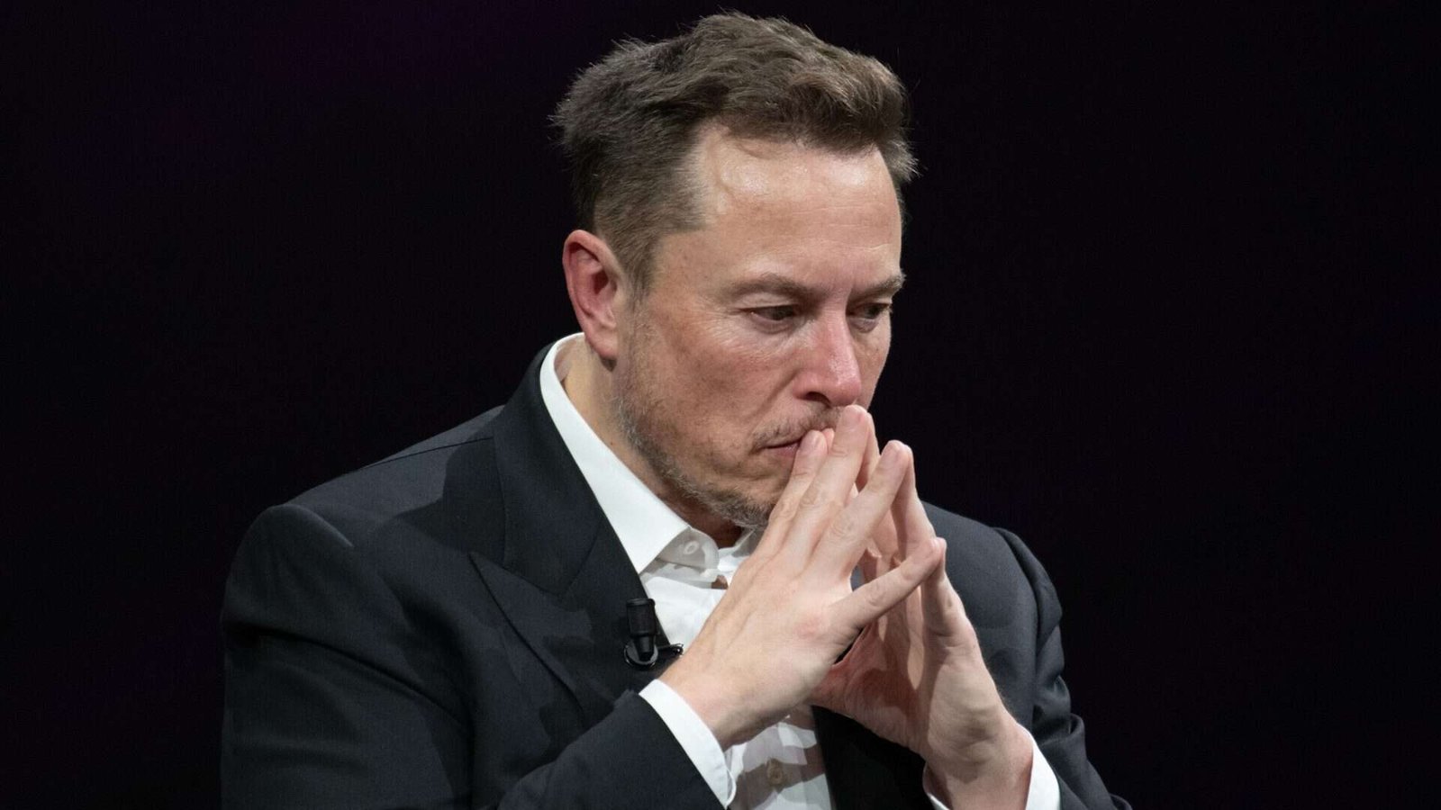 Elon Musk com as mãos na frente do rosto e expressão preocupada