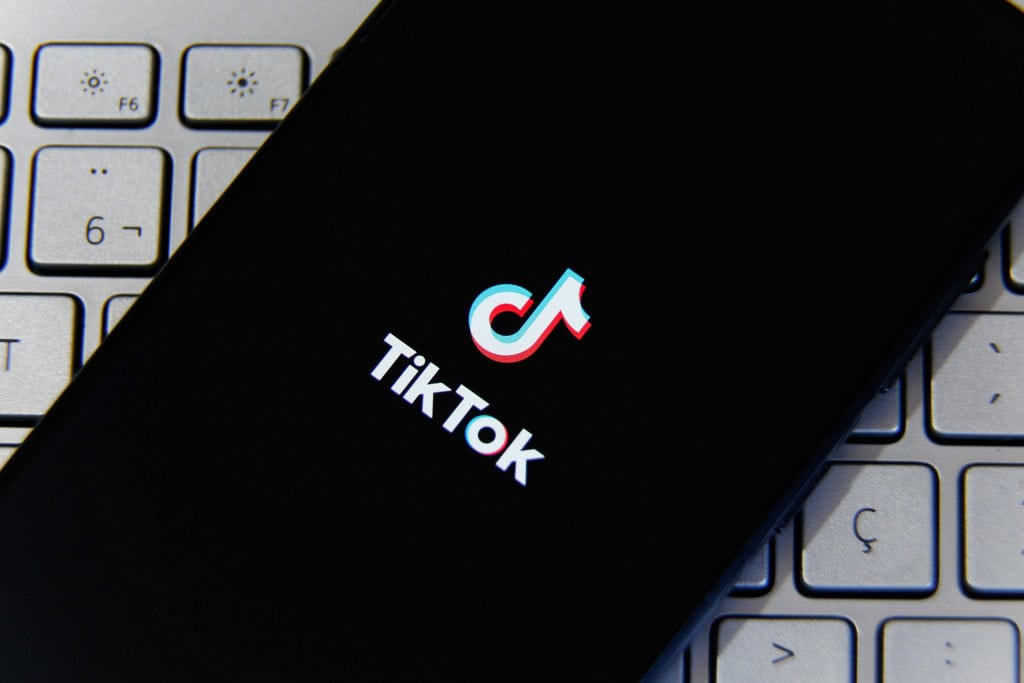 Logo do TikTok em um smartphone que está em cima de um teclado de computador