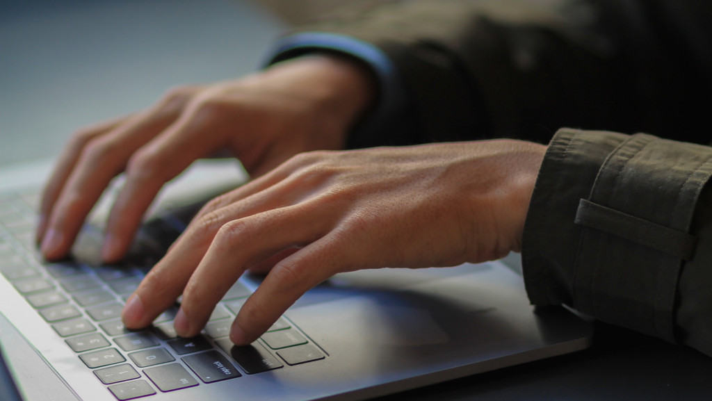 mãos de um homem em teclado de computador