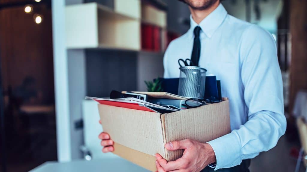 Homem carregando caixa com as suas coisas porque foi demitido