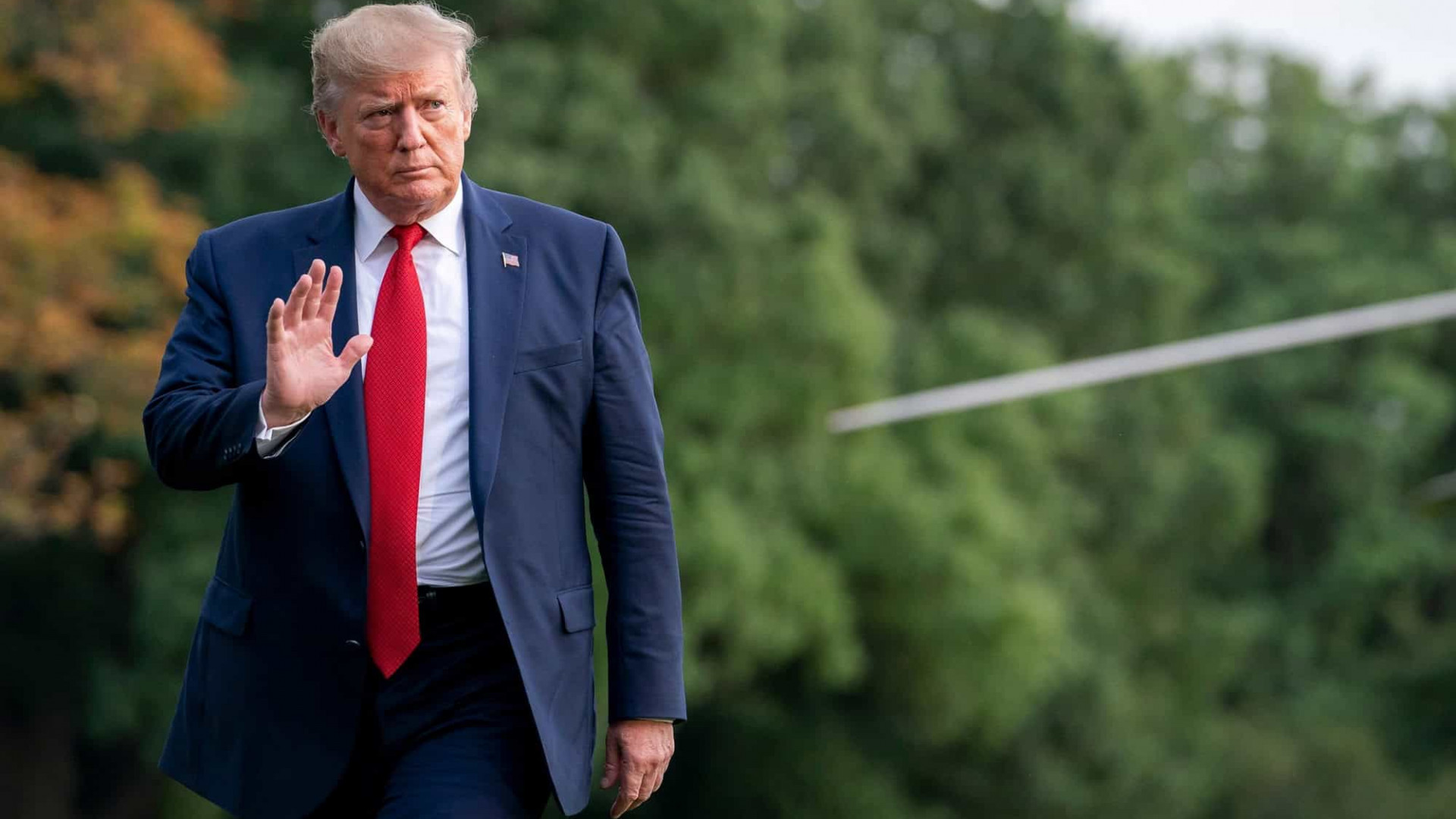 Donald Trump com a mão erguida enquanto anda