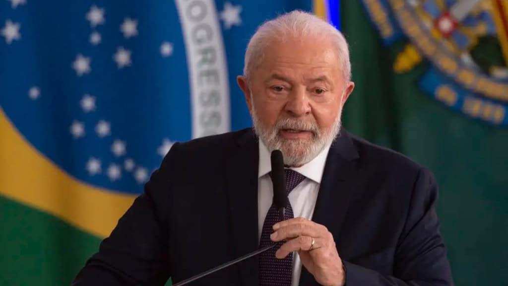 Presidente Lula discursando na frente de bandeira do Brasil