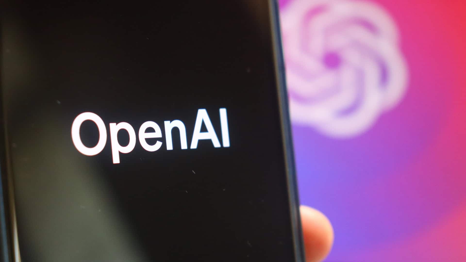 Logo da OpenAI em um smartphone e ao fundo