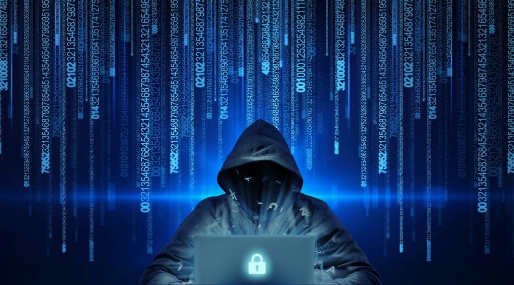 Pessoa com capuz atrás de um notebook