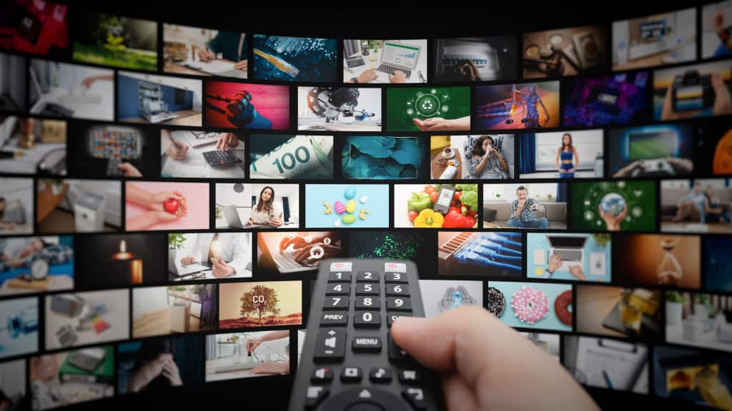 Mídia conceito vídeo parede com telas pequenas, serviço de streaming ou conceito VOD. Controle remoto em mãos