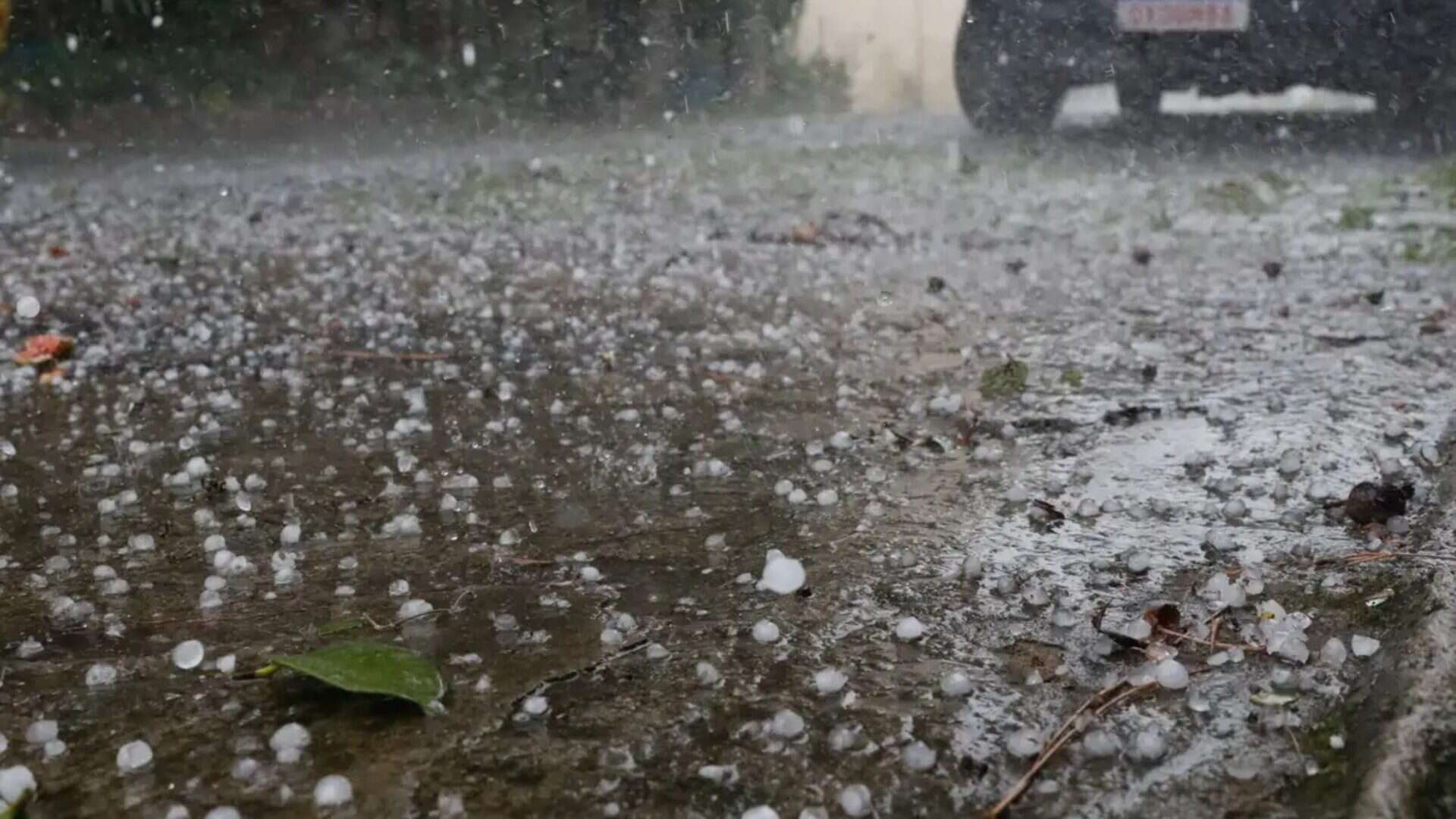 Rua cheia de pedrinhas de gelo durante chuva de granizo